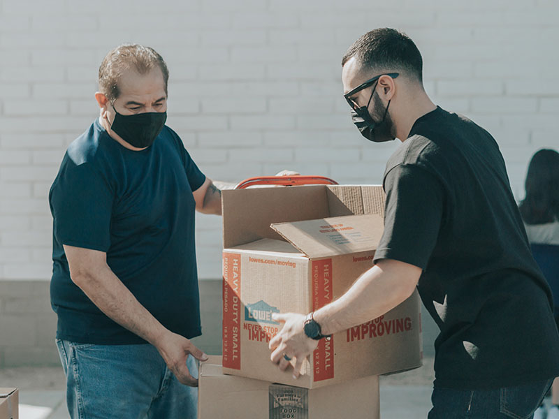 Can You Use a Cardboard Box as Checked Luggage? 1 Two men carrying a single cardboard box