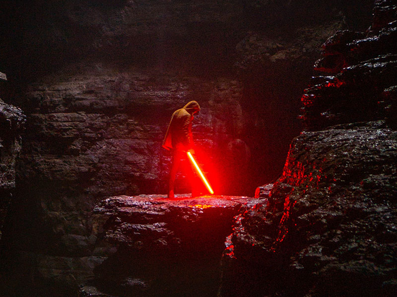 Can You Bring Disney Lightsabers on Planes? 1 man using a red lightsaber replica in a dark cave